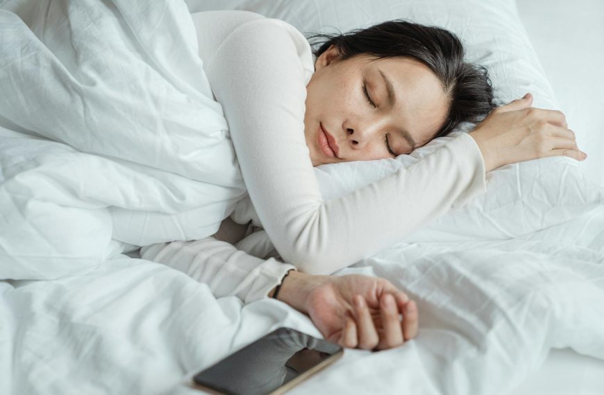 Woman sleeping in bed near smartphone
