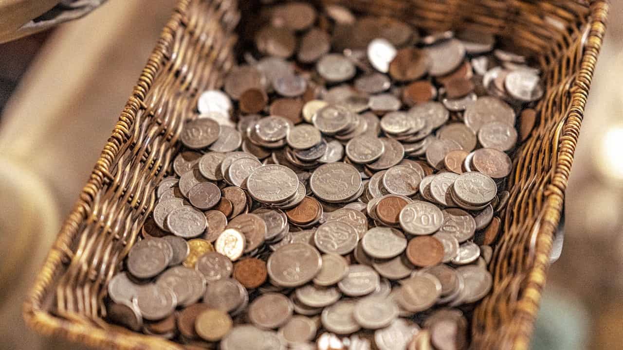 small woven basket, filled with loose change, assorted coins, mixed denominations, rustic tabletop, casual storage