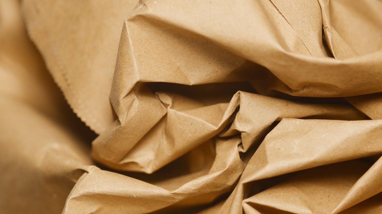 Torn brown wrapping paper, rough edges, crumpled texture, natural earthy tone, simple recyclable material