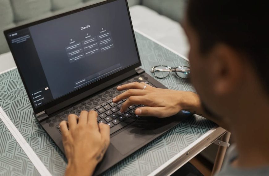 person typing on a laptop, AI dashboard on screen, seated at a desk, focus on hands and keyboard, blurred background, casual indoor setting