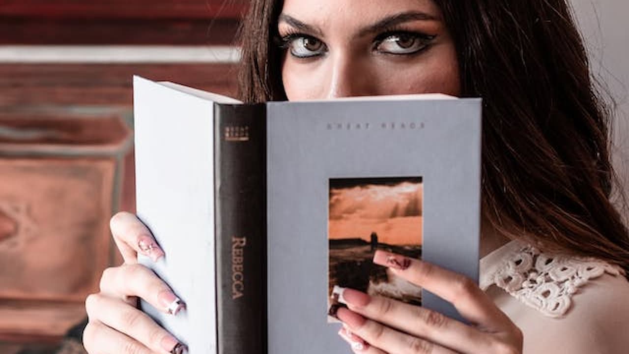 Woman holding an open book, partially hiding her face, intense eyes peeking over the top, indoor setting, soft lighting, blurred background
