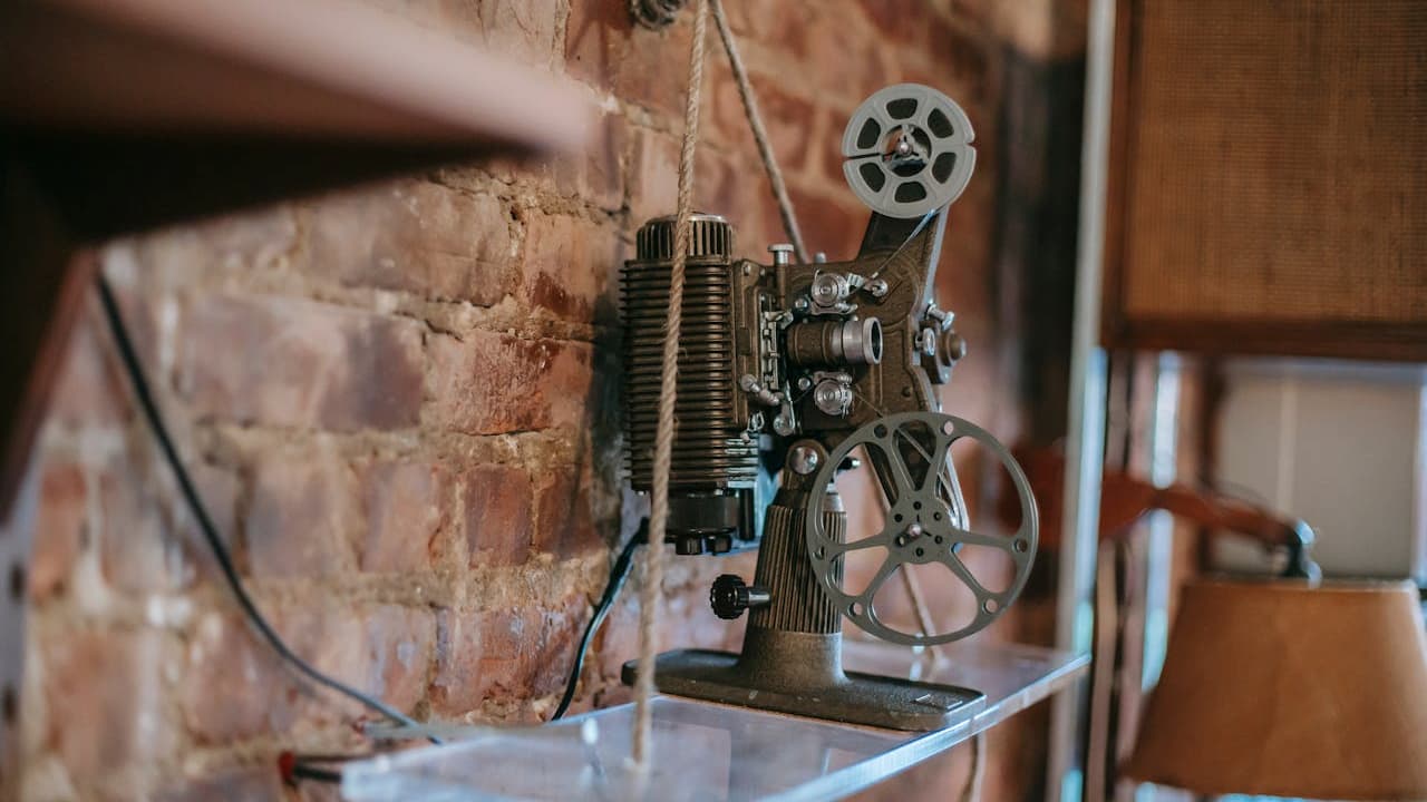Vintage film projector on a clear shelf, metallic and mechanical in design, set against a rustic wooden wall, electrical cord visible and plugged in, surrounded by warm ambient lighting, evokes a nostalgic cinematic atmosphere