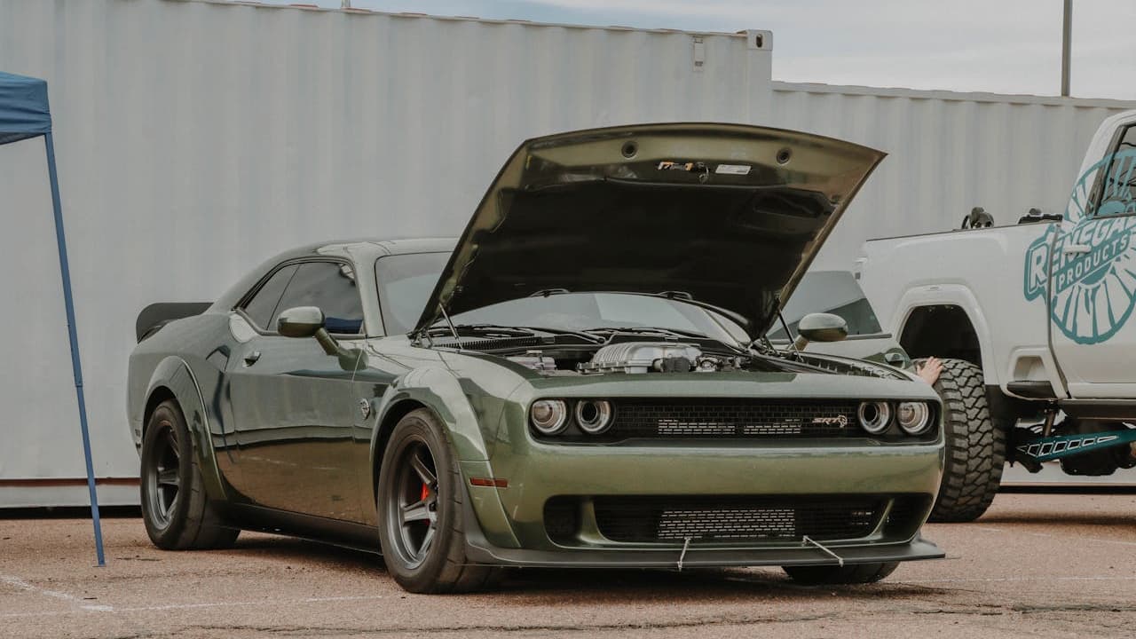 1970 Dodge Challenger R/T, classic American muscle car, bright paint finish, dual hood scoops, chrome bumpers, bold front grille, raised rear stance, vintage mag wheels, parked on pavement