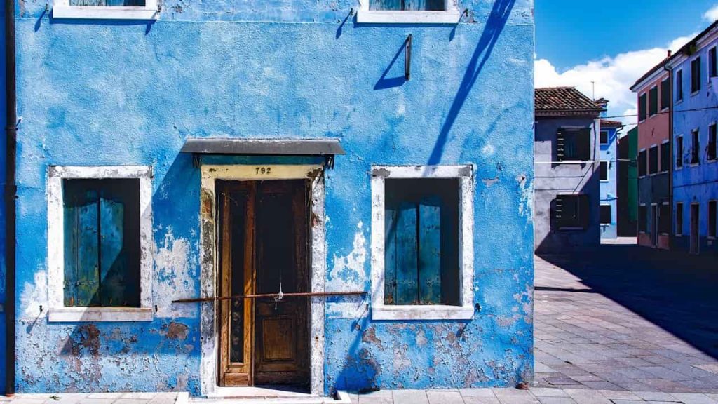 door stuck or hard to close, humidity-related warping, need for replacement or repair, structural shift in house, homeowner inspecting damage, energy loss due to poor seal
