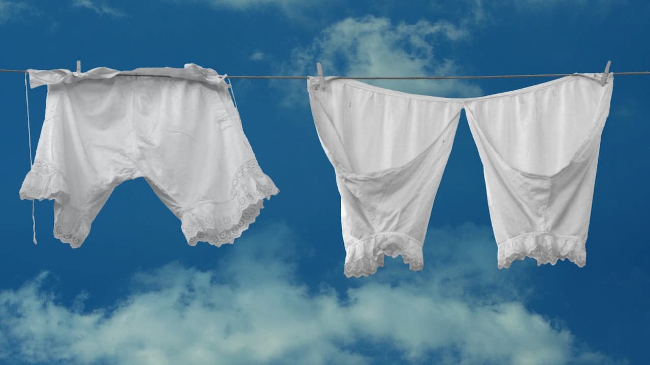 White laundry hanging on a clothesline, blowing in the wind, bright blue sky with scattered clouds in the background