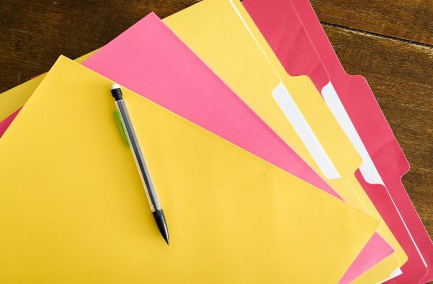 stacked folders, assorted colors, labeled tabs, organized by category, plastic or paper material, stored on shelf or drawer, color-coded for easy identification