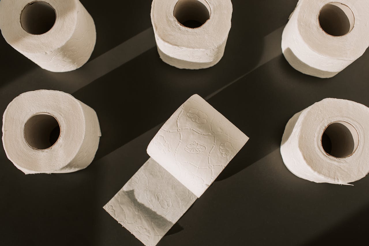 toilet paper rolls, white soft tissue, cylindrical shape, perforated sheets, stacked neatly, bathroom setting, clean and unused