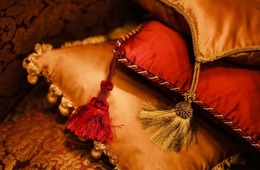 Close-up of decorative throw pillows in gold and red with tassels and ornate trim