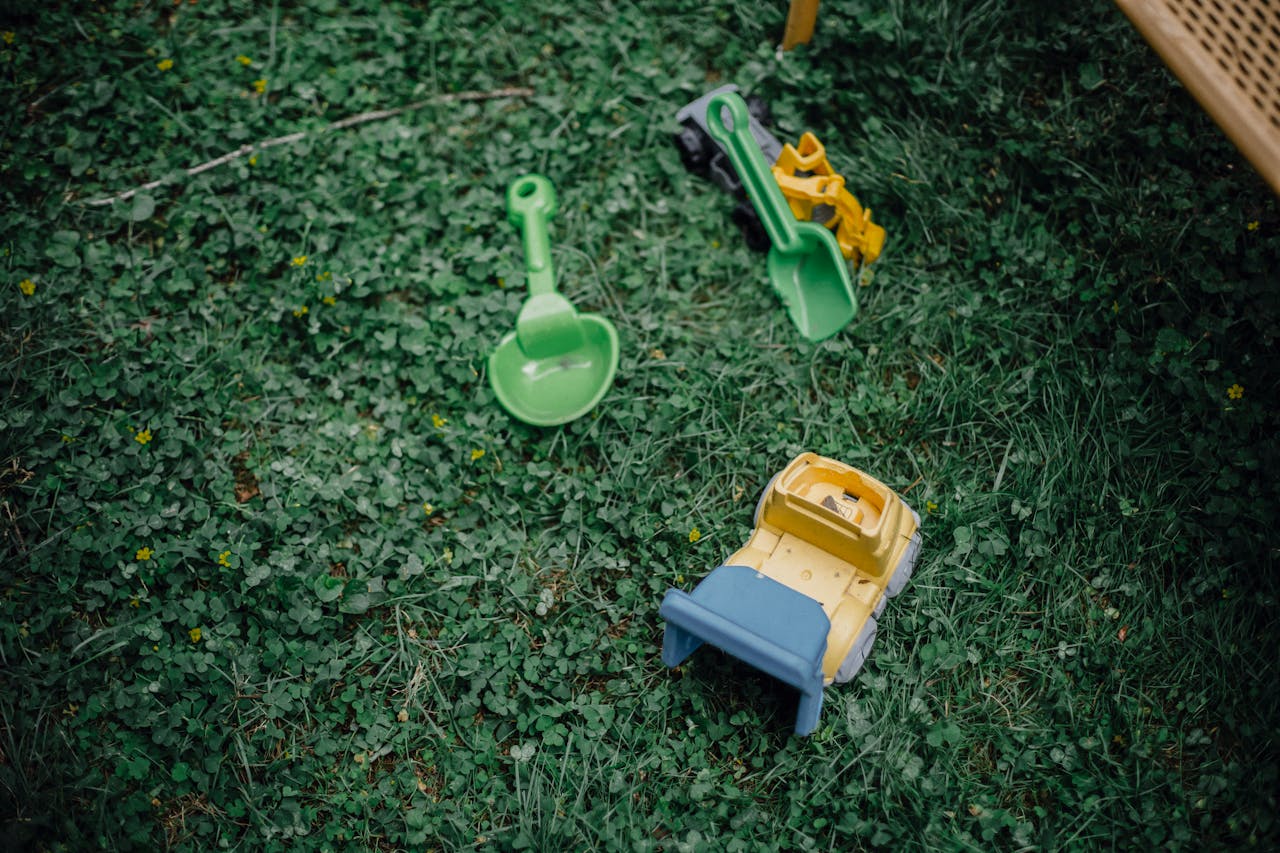 Plastic toy shovel and toy truck scattered on a grassy yard