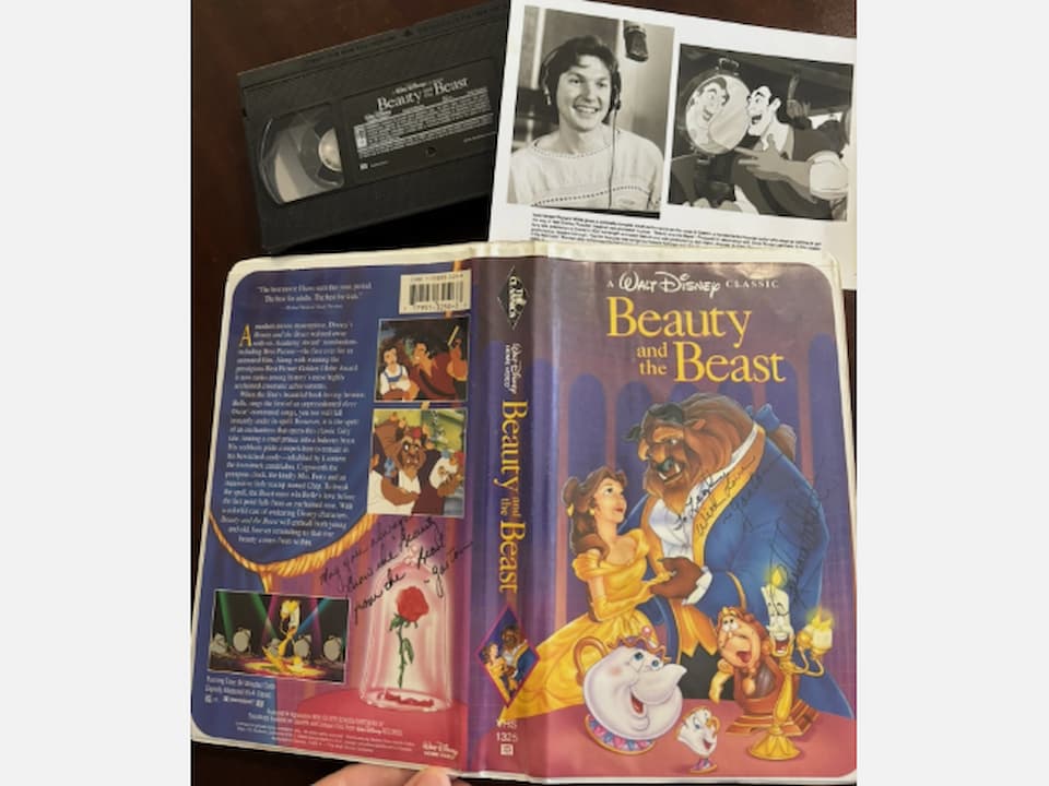 Disney’s Beauty and the Beast Black Diamond VHS edition, open clamshell case showing front and back cover artwork, Belle and Beast featured in a ballroom scene, additional character illustrations including Lumière and Mrs. Potts, VHS tape labeled “Beauty and the Beast,” black and white insert with voice actor photo and animation still, resting on a dark wooden surface