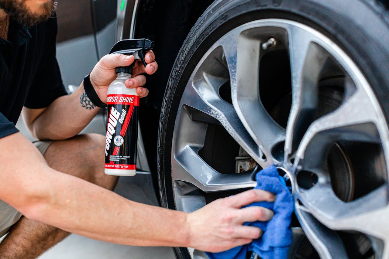 A Person Using a Spray Bottle on a Car Wheel
