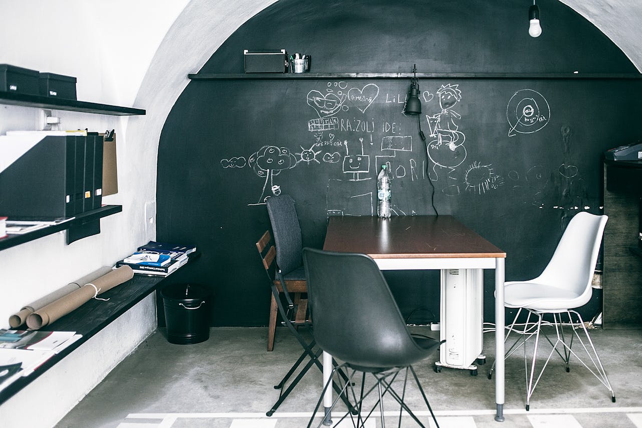 Furniture near chalkboard with illustrations in empty workspace