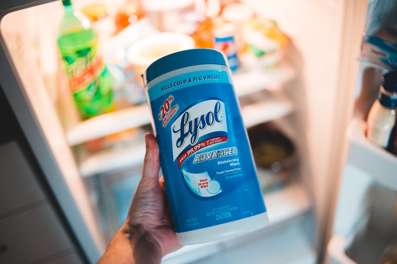Unrecognizable person demonstrating sterile wipes container near refrigerator