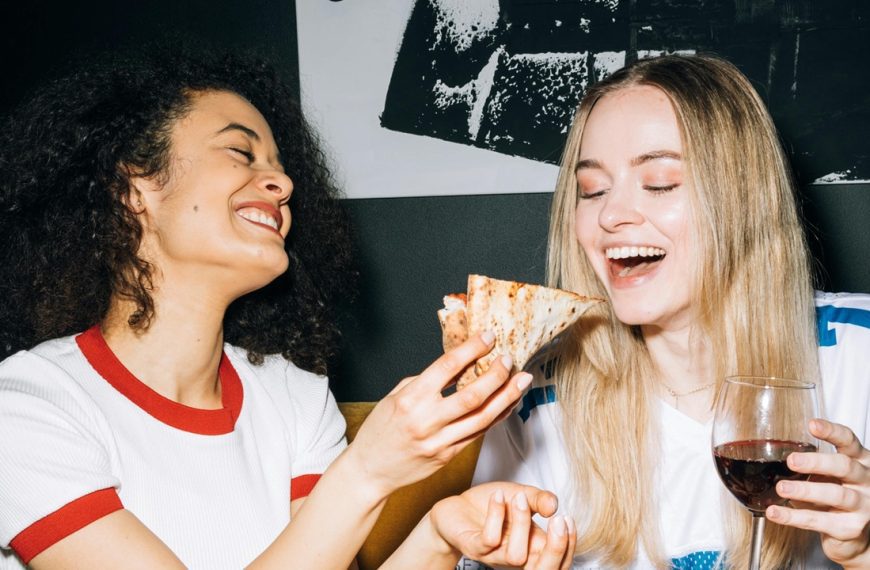 Two women friends eating snacks and drinking wine together
