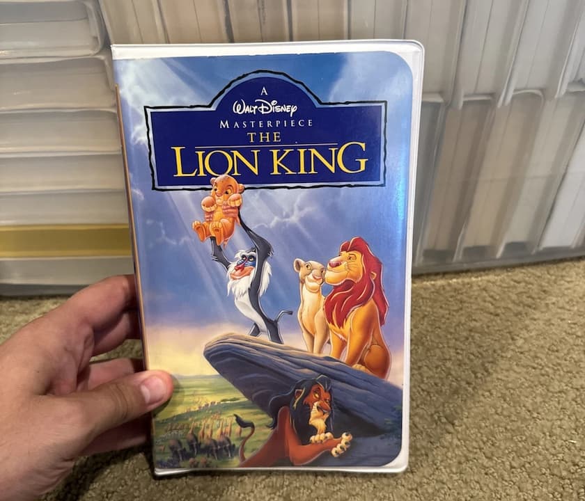 The Lion King Masterpiece Collection VHS, Rafiki holding Simba on cover, golden sunrise, clamshell case, labeled tape beside it