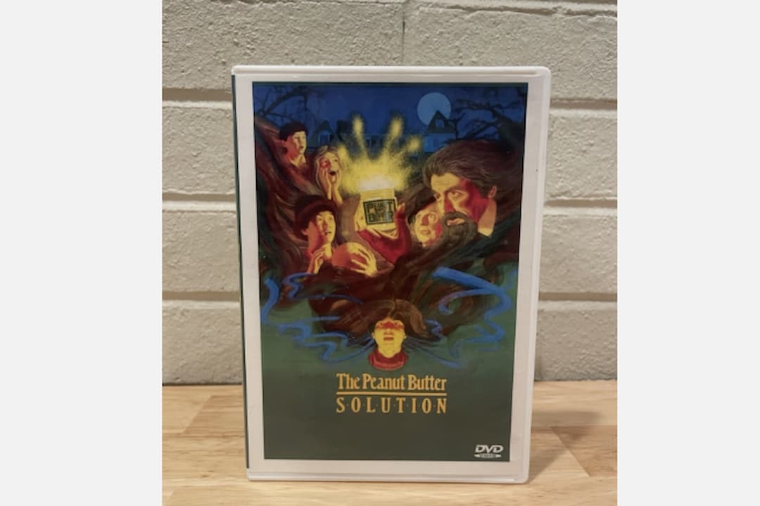 VHS tape and case for The Peanut Butter Solution (1985), surreal illustrated cover showing a frightened boy with exaggerated hair, whimsical and eerie tone, vintage children’s film packaging, bold title font