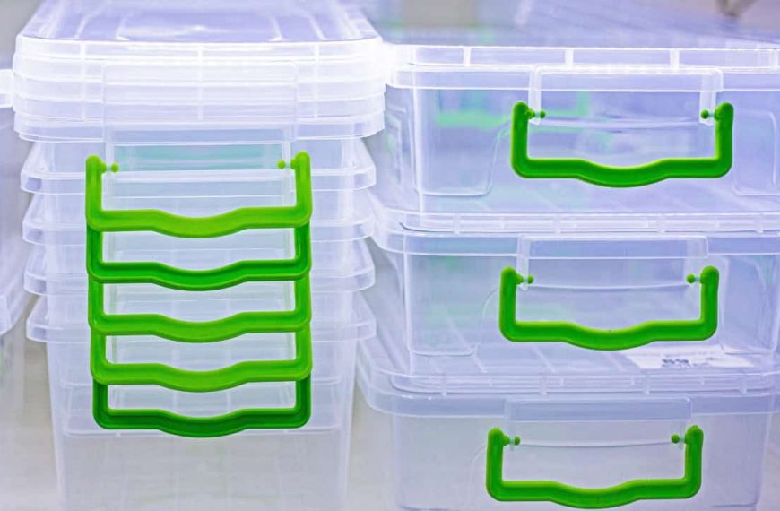 Stacked transparent storage boxes with green handles, organized containers with visible lids, close-up of plastic bins for storage, neatly arranged storage bins with color-coded handles
