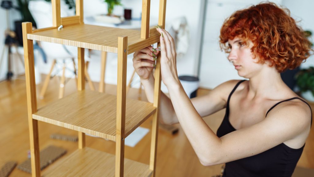RepurposeDIY manual home furniture assembly. young attractive red-haired woman is engaged in assembling furniture at home with own hands