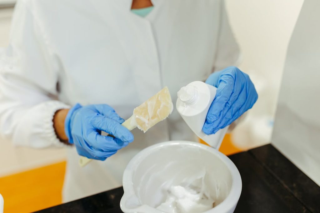 Hands in Gloves Holding Tube and Spoon with Cream