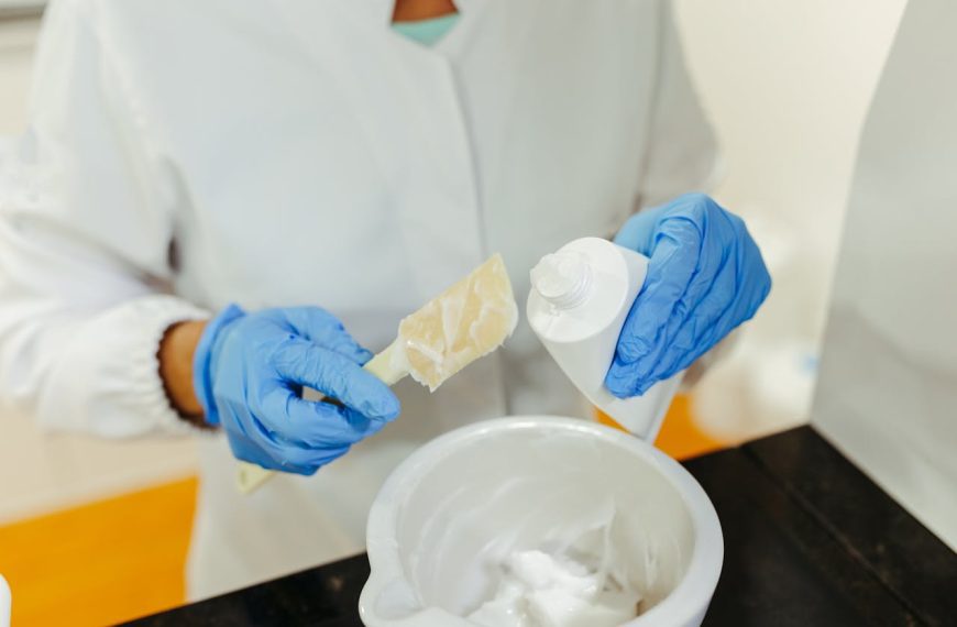 Hands in Gloves Holding Tube and Spoon with Cream