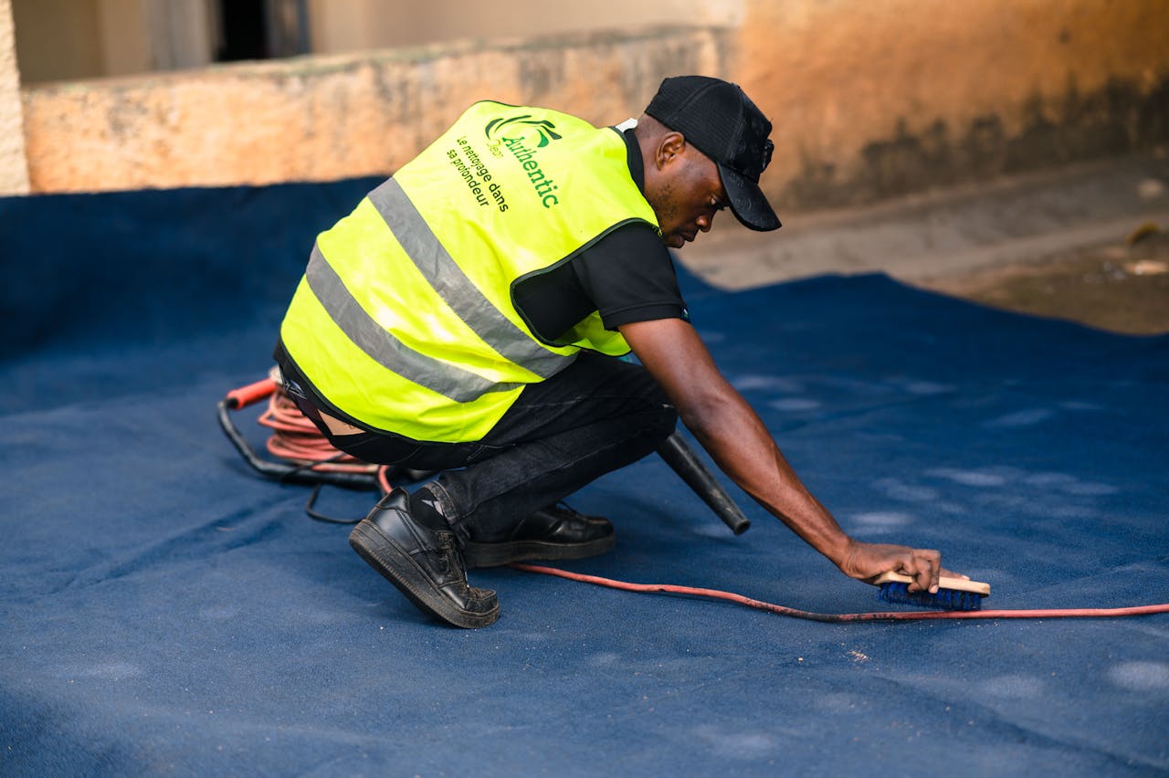 Worker Cleaning Carpet with Brush in Outdoor Setting