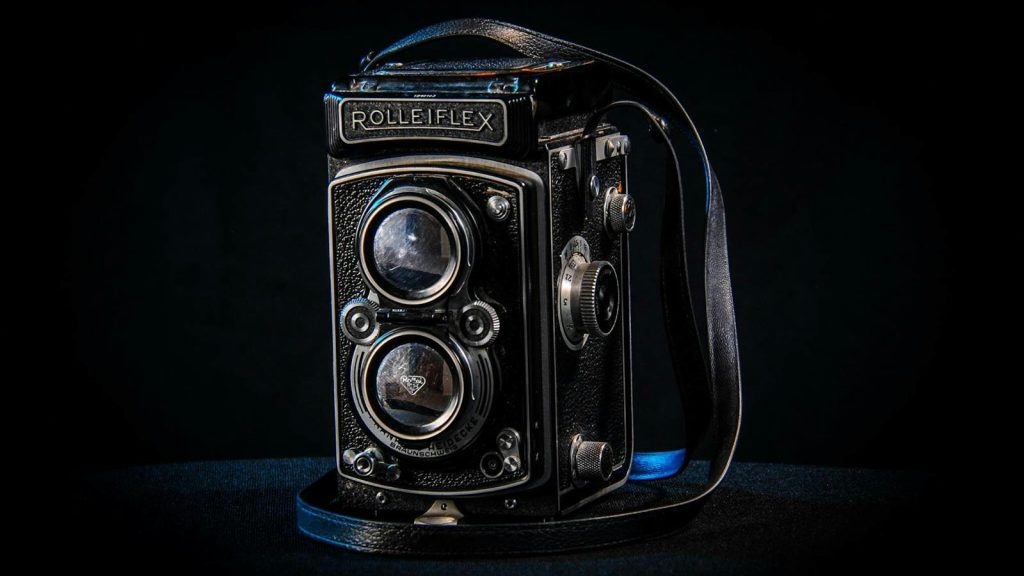 Classic Rolleiflex twin-lens reflex camera with a dark backdrop, highlighting its vintage design.