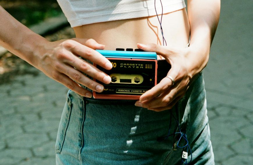 Woman holding a cassette player on a sunny day in New York City, capturing vintage vibes.