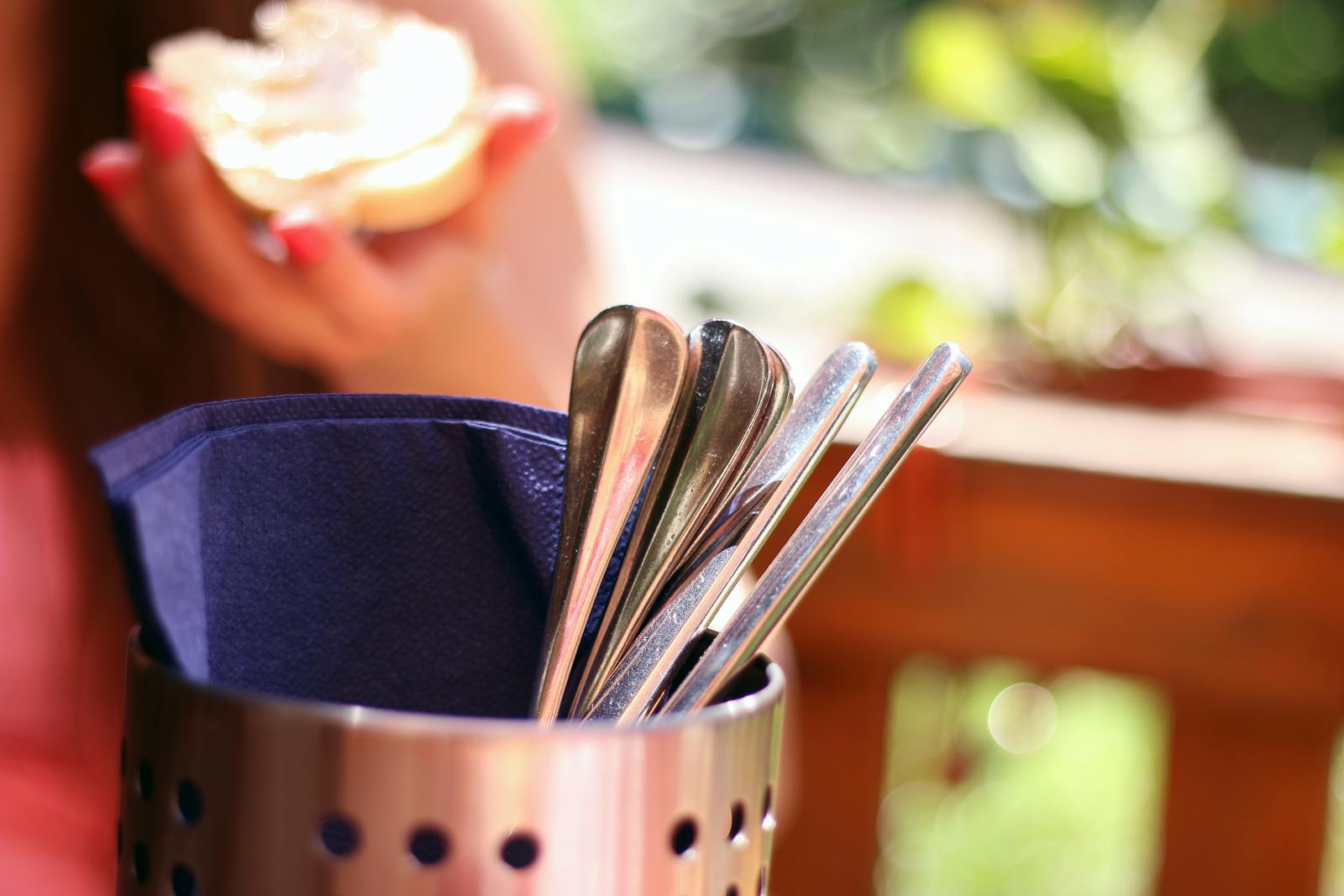 Close-up of stainless steel cutlery in a holder during an outdoor dining setting.