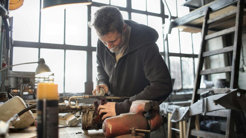 A focused craftsman operating machinery in a cluttered workshop setting.