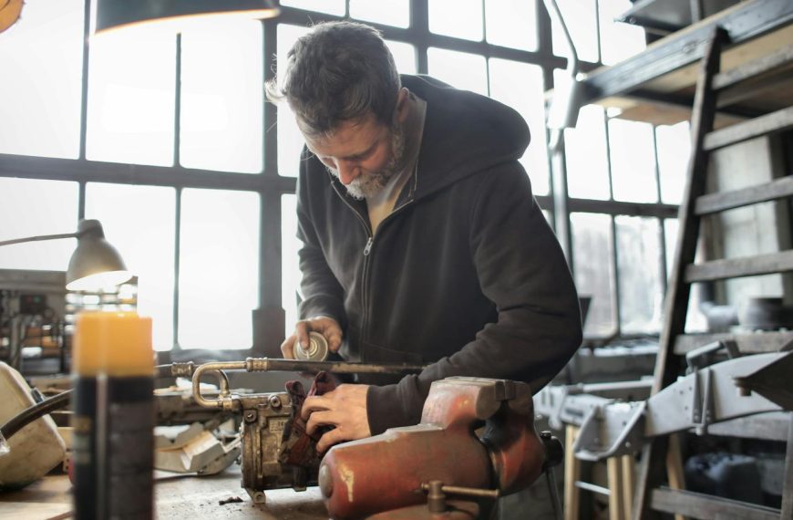 A focused craftsman operating machinery in a cluttered workshop setting.