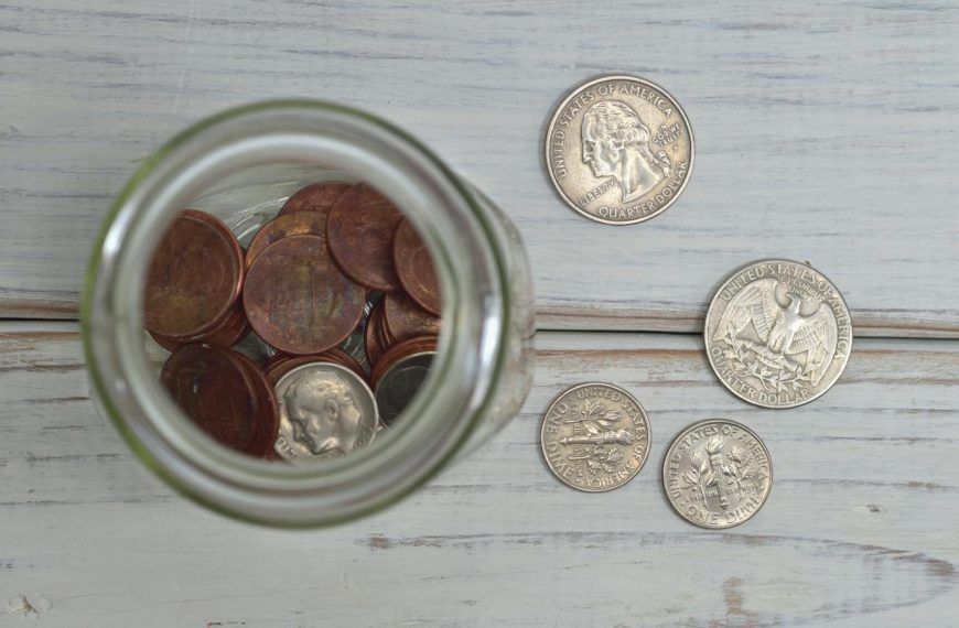 Top view of a jar filled with coins placed on a wooden table, depicting savings.