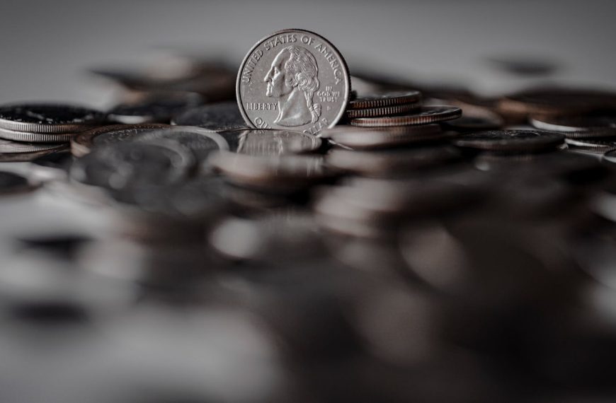 Pile of American coins with a focus on a quarter, symbolizing currency and wealth.