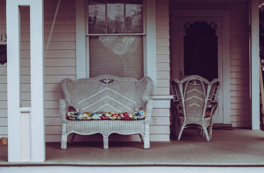 Cozy vintage-style front porch with white wicker chairs and floral cushions.