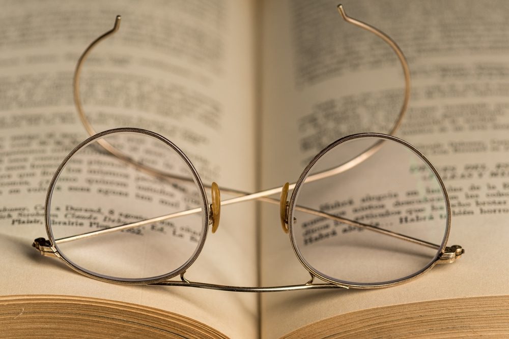 Antique eyeglasses over an old open book. Closeup 