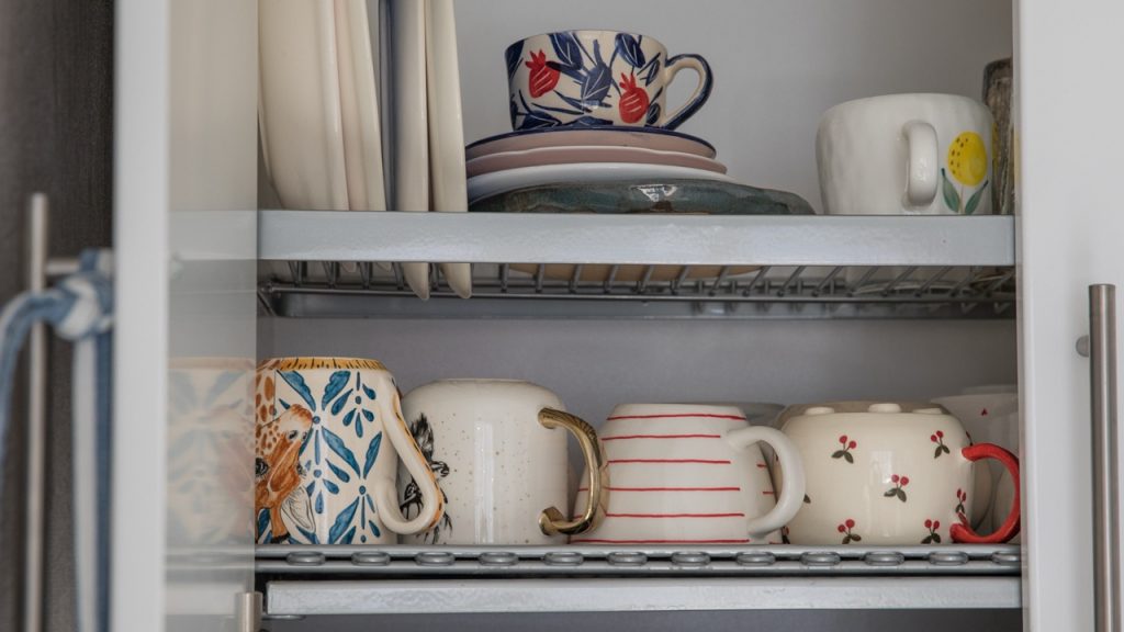 Beautiful dishes on a drying rack in a kitchen cabinet