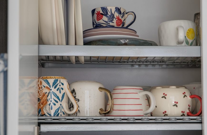 Beautiful dishes on a drying rack in a kitchen cabinet
