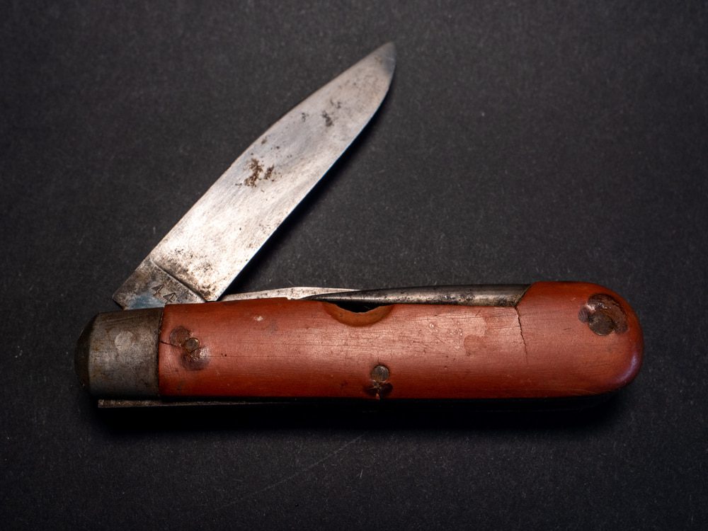 vintage antique swiss military pocket knife with used and rusty blade from the second world war black background