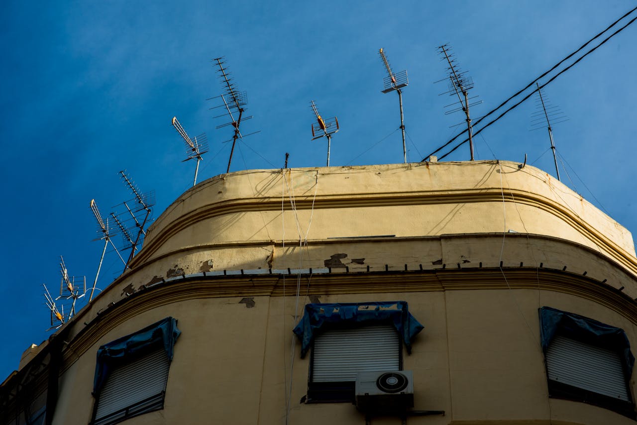 Urban Building with TV Antennas Against Blue Sky