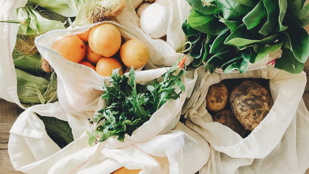 fresh vegetables in eco cotton bags on table in the kitchen.