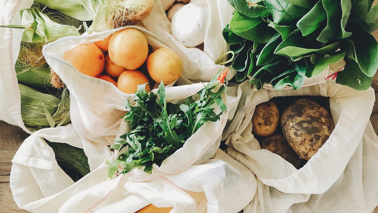 fresh vegetables in eco cotton bags on table in the kitchen.
