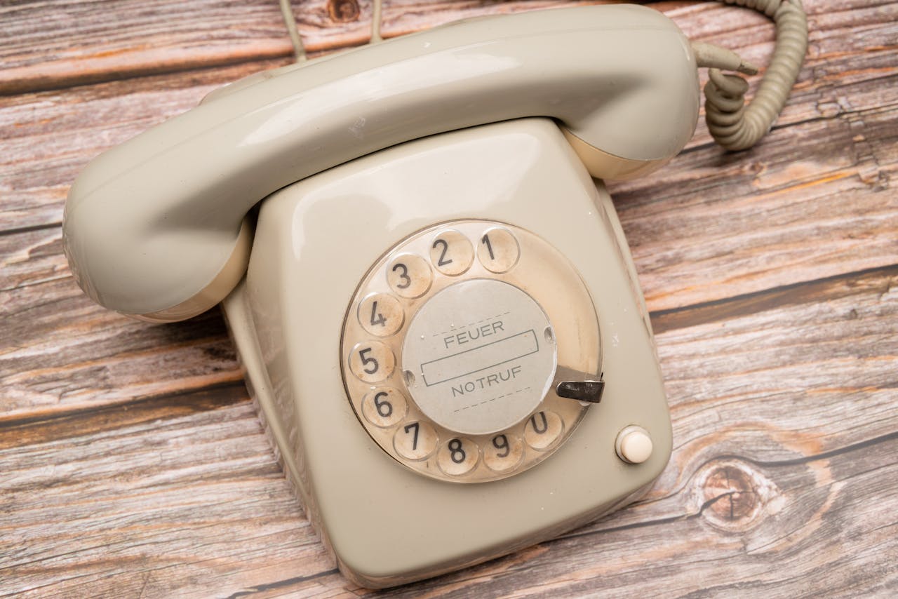 White Rotary Phone on Brown Wooden Table