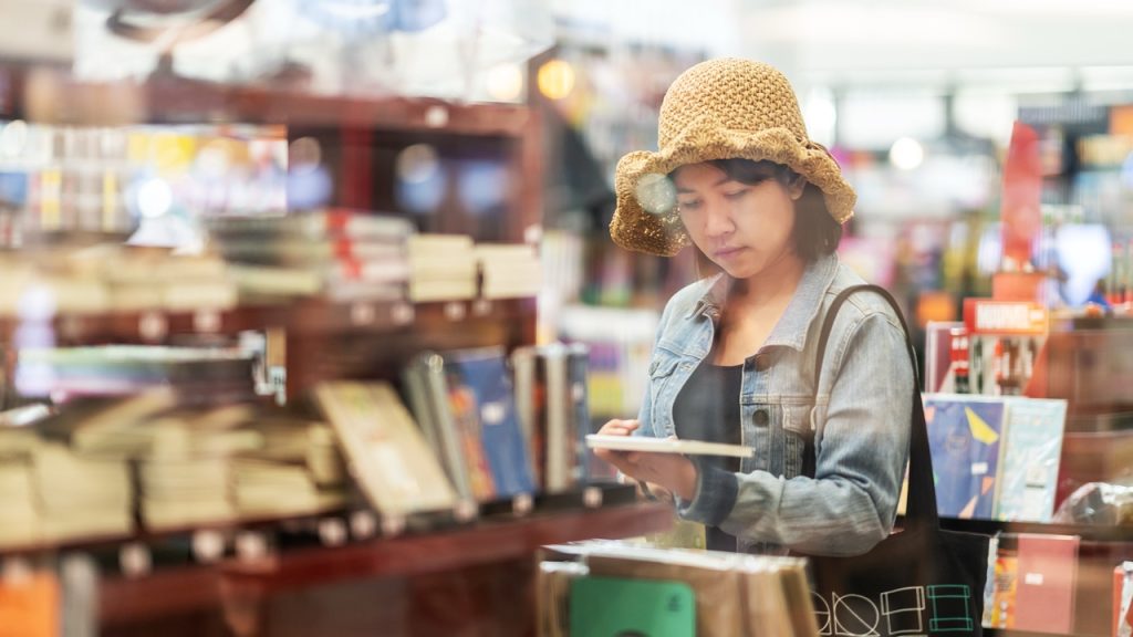 Woman wearing a hat holding book in thrift store