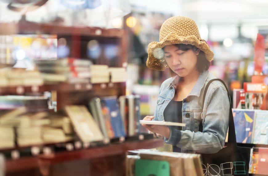 Woman wearing a hat holding book in thrift store