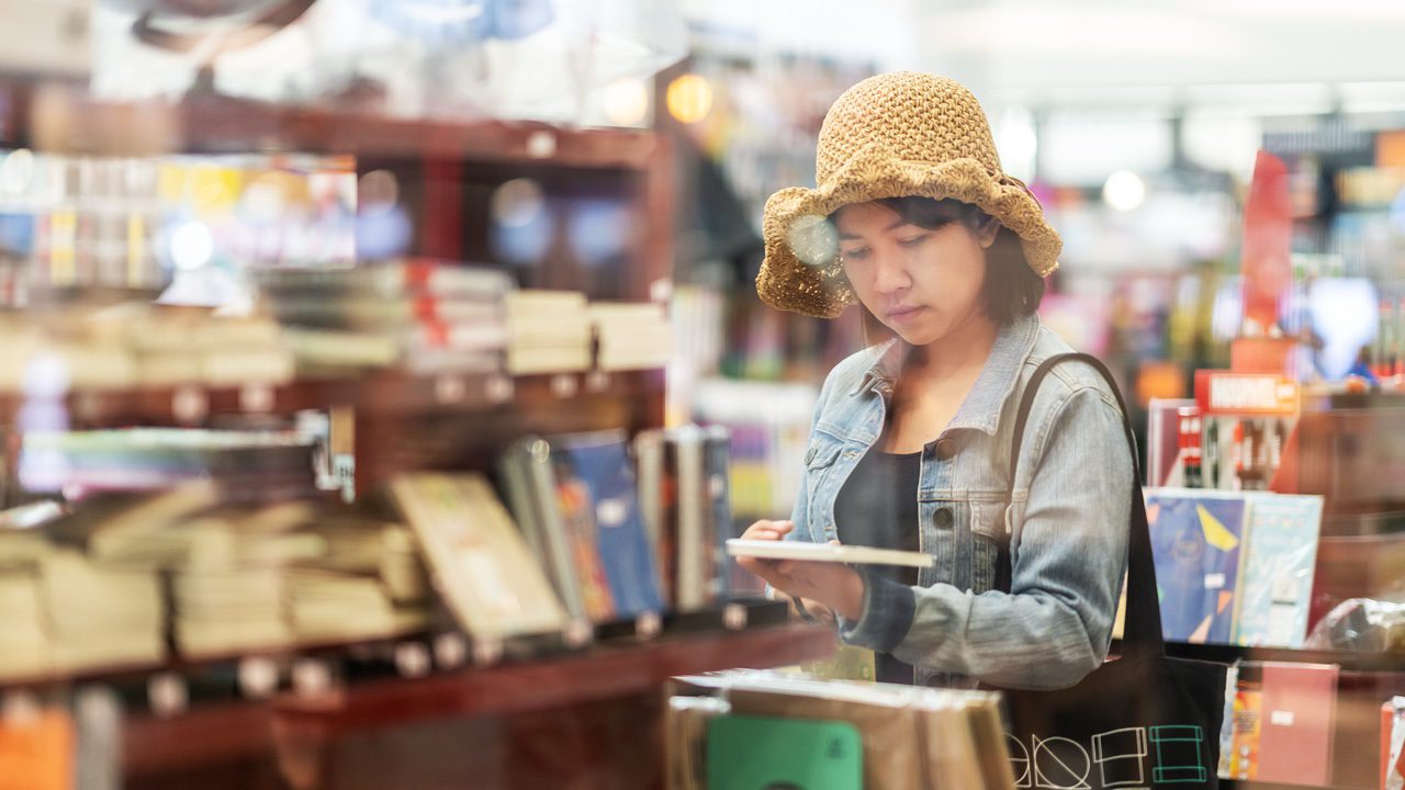 Woman wearing a hat holding book in thrift store