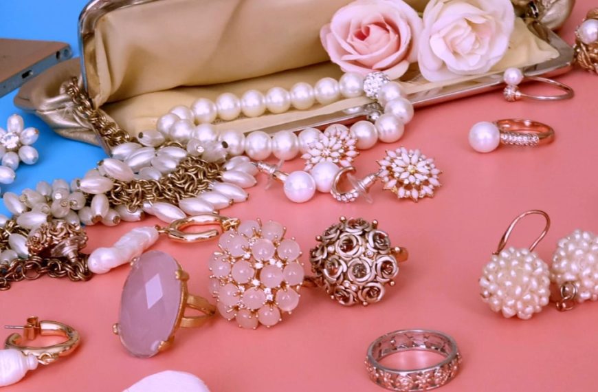 Jewelry gold white pearl Luxury Glamour fashion costume jewelry cosmetics cases rings earrings bracelet with red roses on blue and pink coral background women accessories