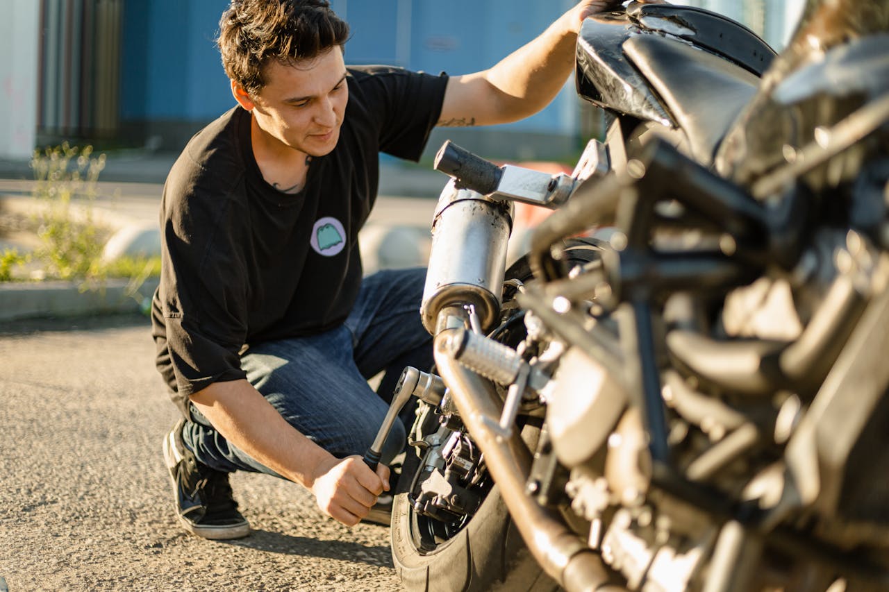 Man Holding a Socket Wrench Fixing a Black Motorcycle