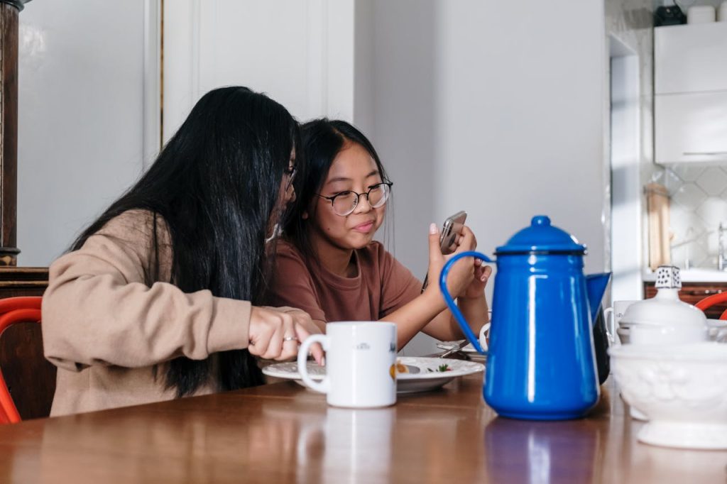 Woman in Brown Sweater Sitting Beside Brown Wooden Table