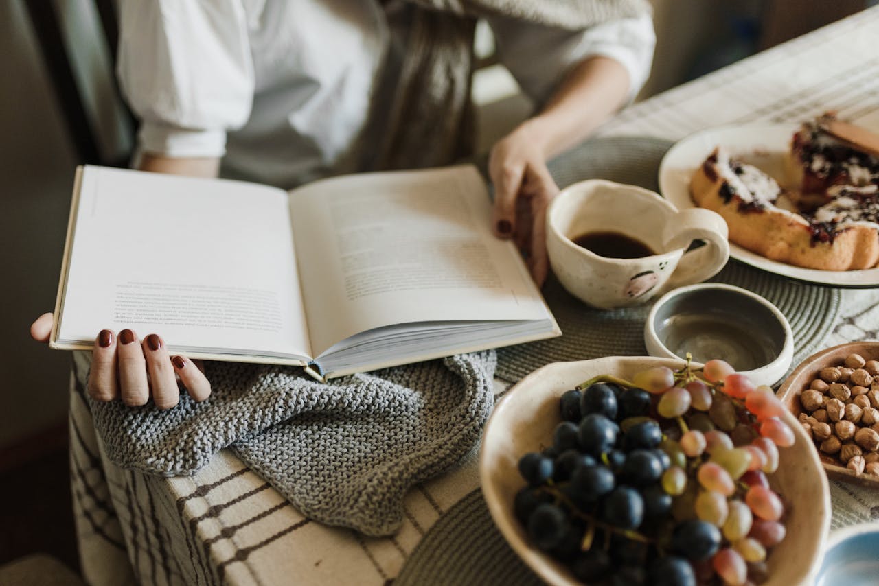 A Person Holding a Book on a Table with Food