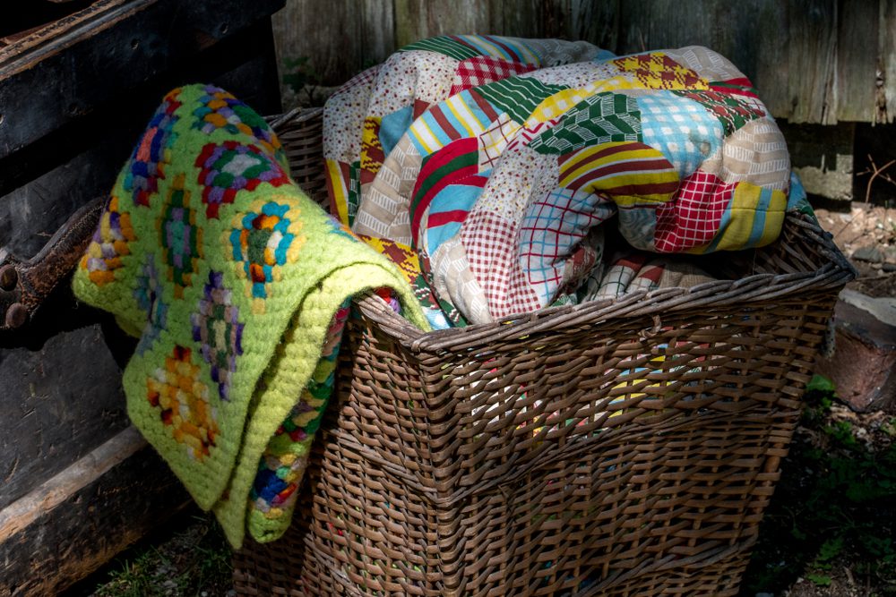 old wicker basket filled with hand made quilts and blankets