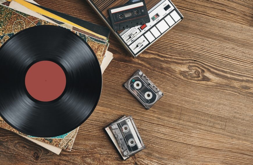 Vinyl records, cassette tapes and cassette recorder on wooden table. Retro music style. 80s music party. Vintage style. Analog equipment. Stereo sound. Back to the past